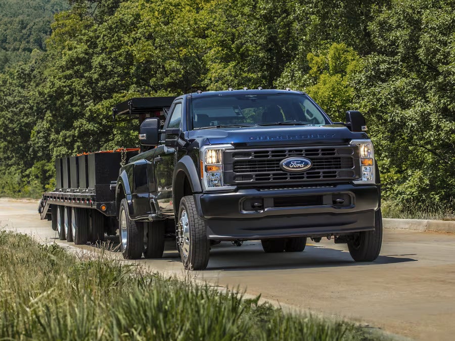 A black truck pulling a trailer on the road.