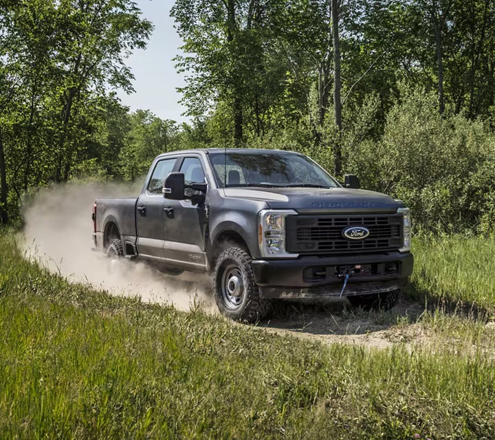 A gray truck driving on a dirt road.