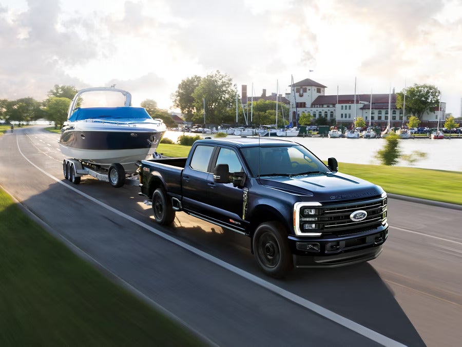 A black truck pulling a boat down the road.