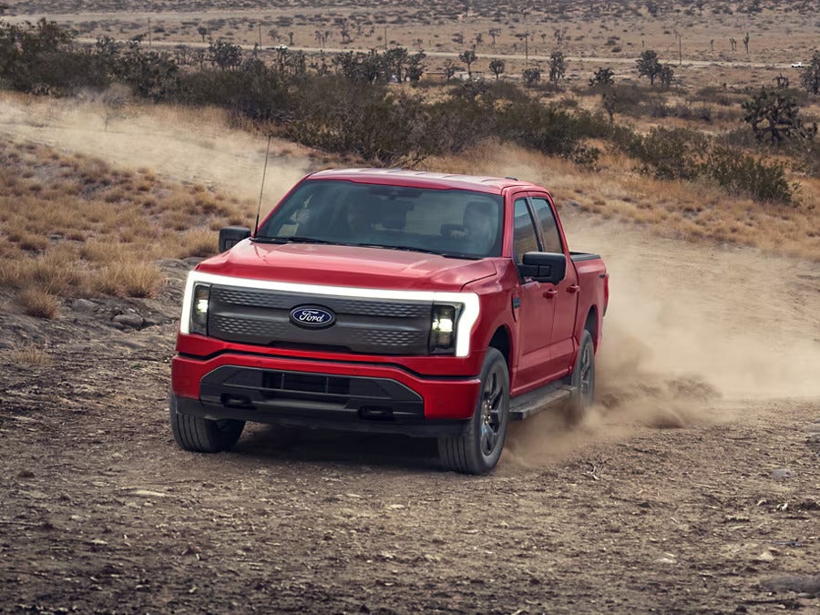 2024 Ford F-150 Lightning driving on a dusty desert trail, demonstrating its off-road capability.