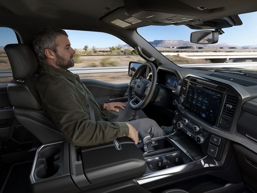 Interior of a Ford F-150 with a man sitting comfortably in the driver’s seat, showing the advanced dashboard and large touchscreen display.