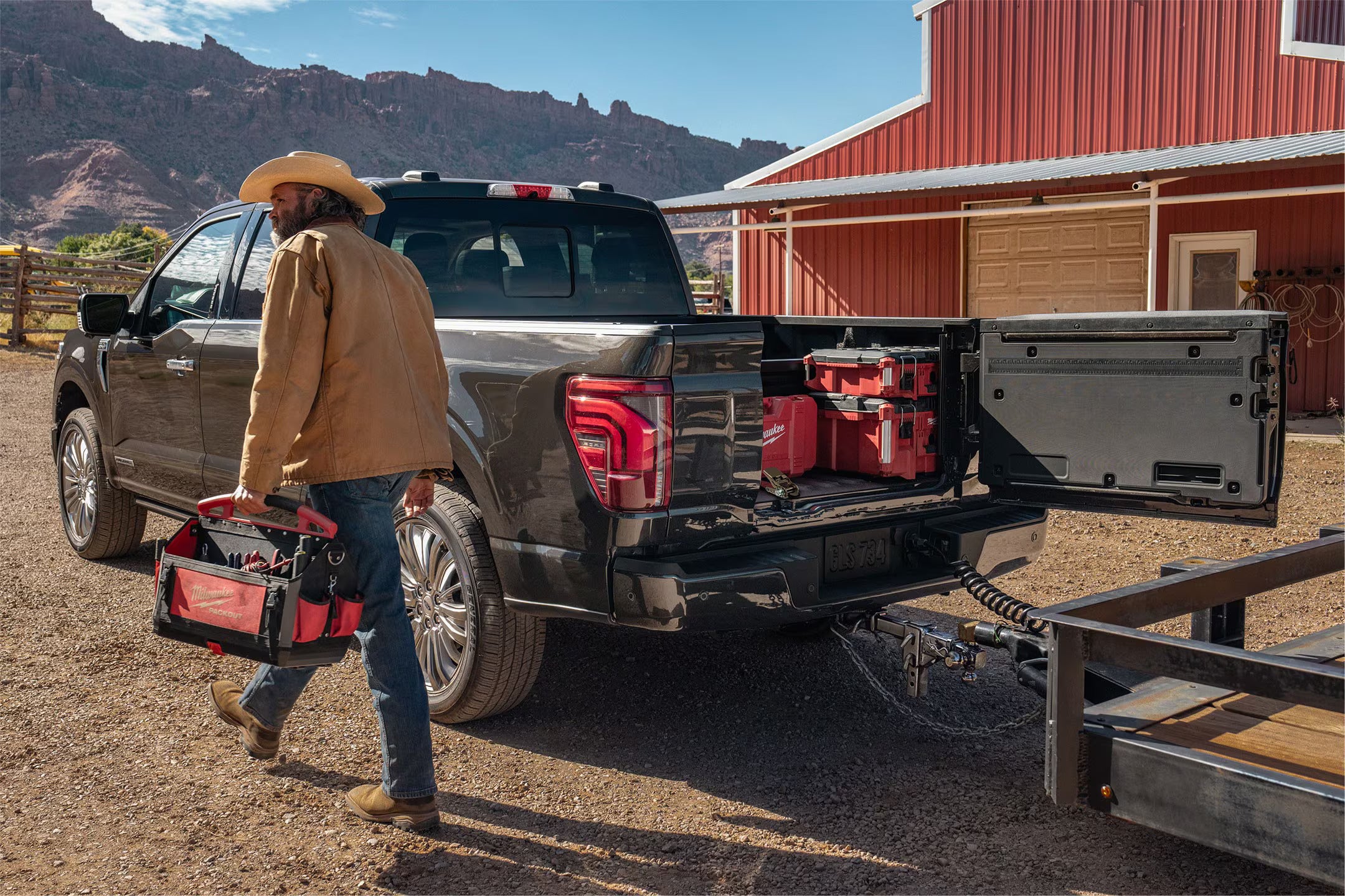 Man walking away from a Ford F-150 with an open tailgate, loaded with tools, on a farm.