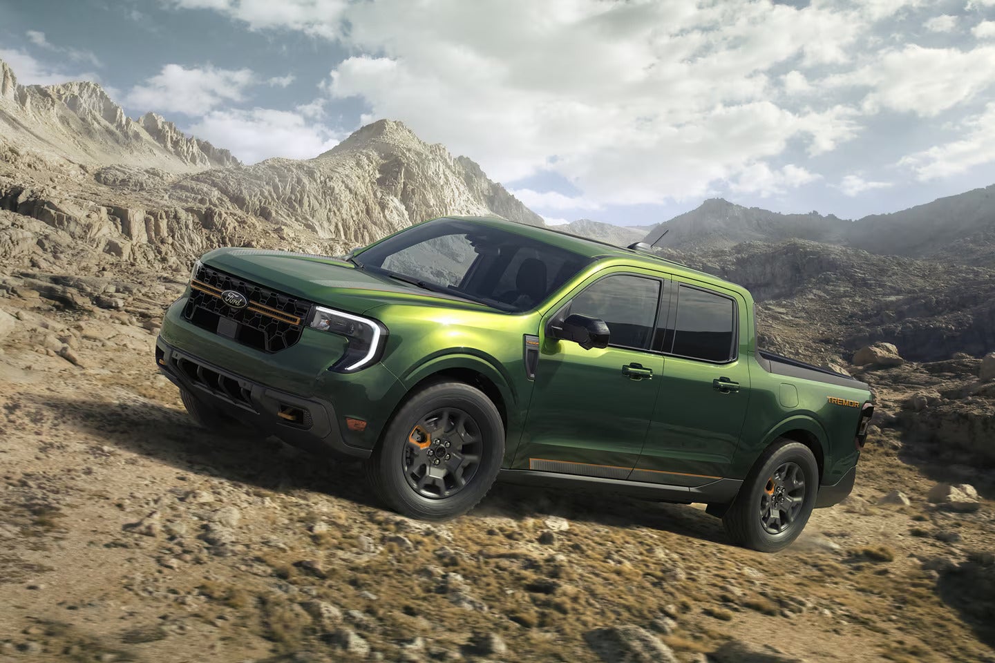 2025 Ford Maverick in a rugged green color driving on a rocky mountain terrain.