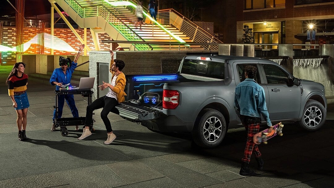 a gray ford maverick driving on a paved road with a scenic background
