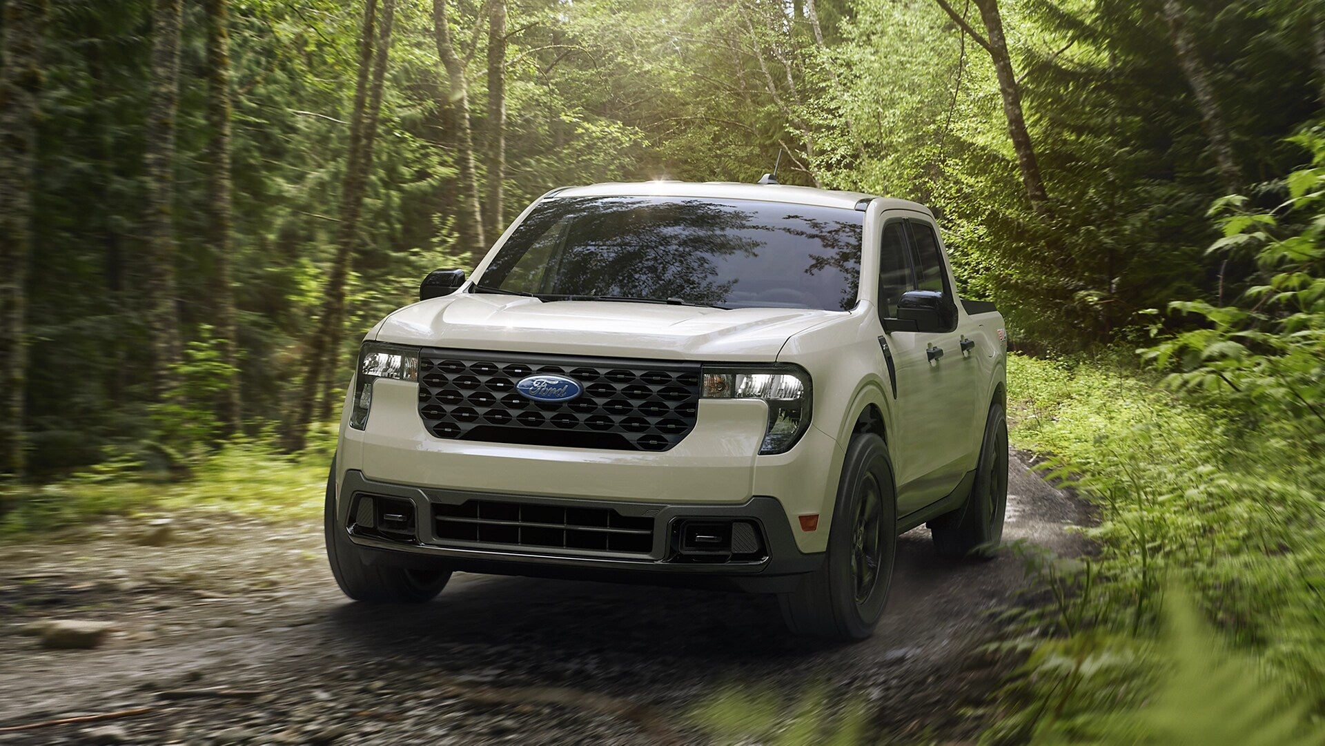a cream colored ford maverick out in the wilderness driving on a trail.
