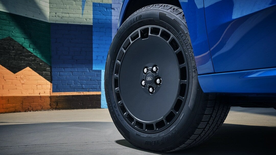 a blue ford maverick truck showcasing close up of the front driver's side tire.