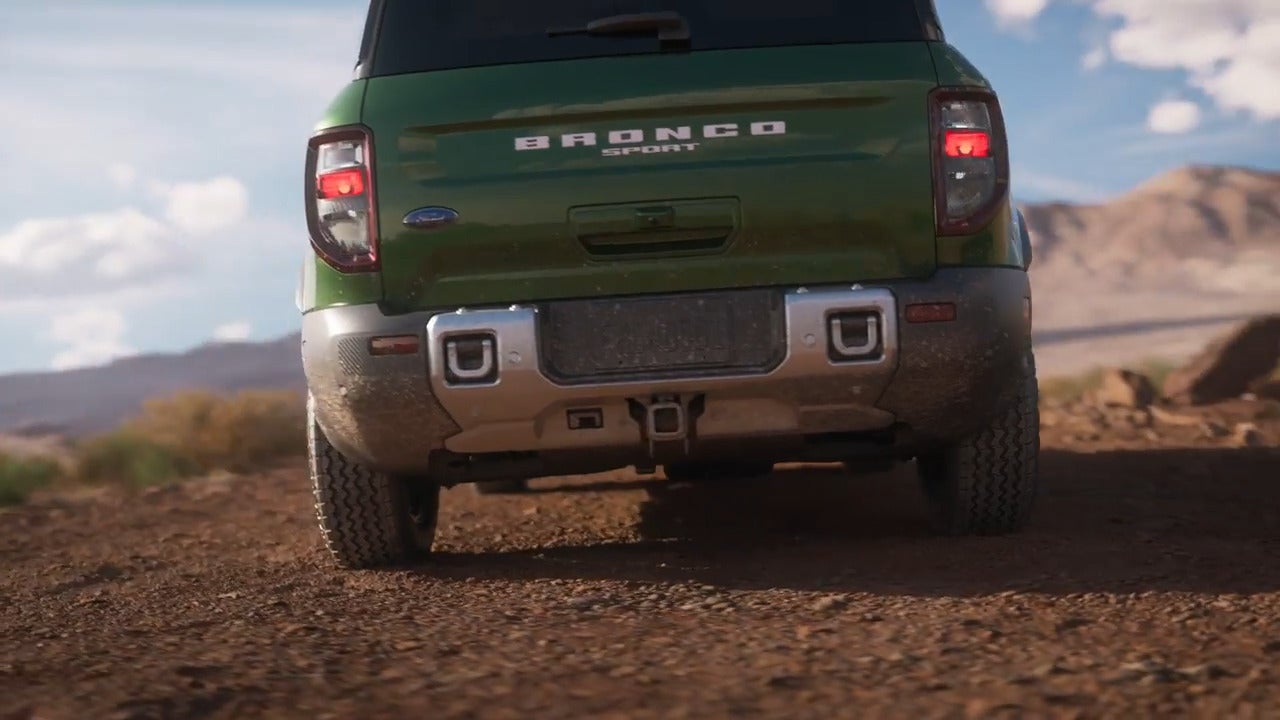 Rear view of the 2025 Ford Bronco Sport driving off-road, showcasing rugged design and dual exhaust.