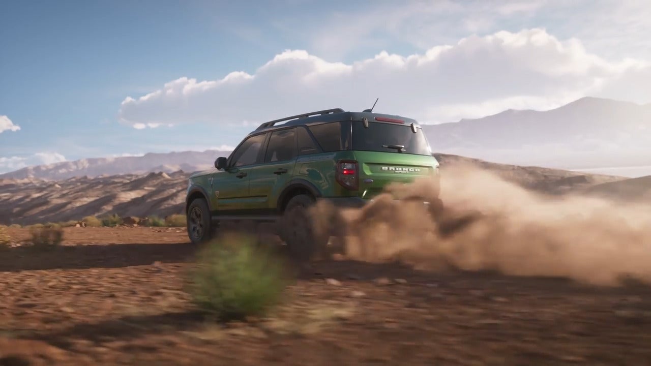 2025 Ford Bronco Sport driving through desert terrain, kicking up dust for an adventurous off-road experience.