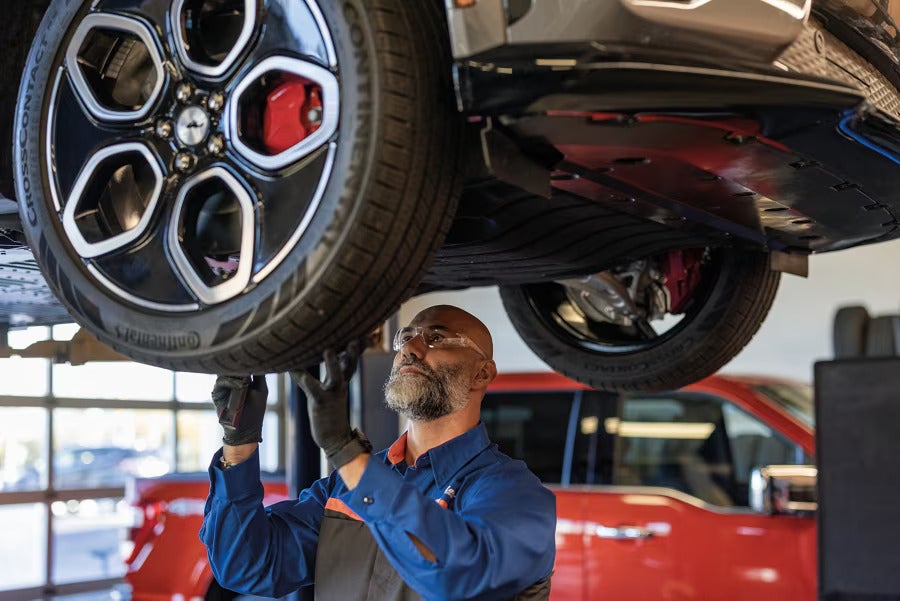 Mechanic performing maintenance on a Ford F-150 Lightning, focusing on the vehicle's wheel and suspension system.