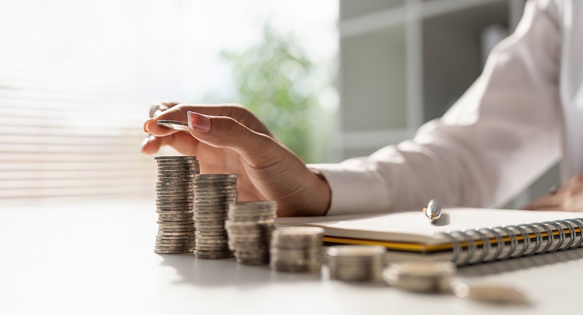 a person counting quarters with a pen and pad of paper